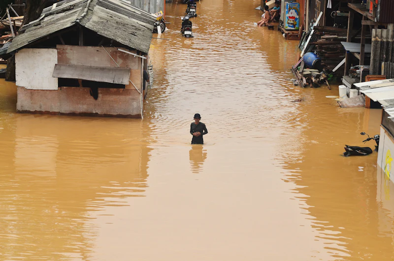 Banjir merendam permukiman, seorang warga berdiri di tengah genangan air